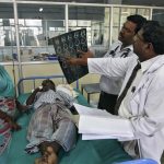 Doctors examine a MRI scan of a patient lying on a bed inside a ward at RGGGH in Chennai