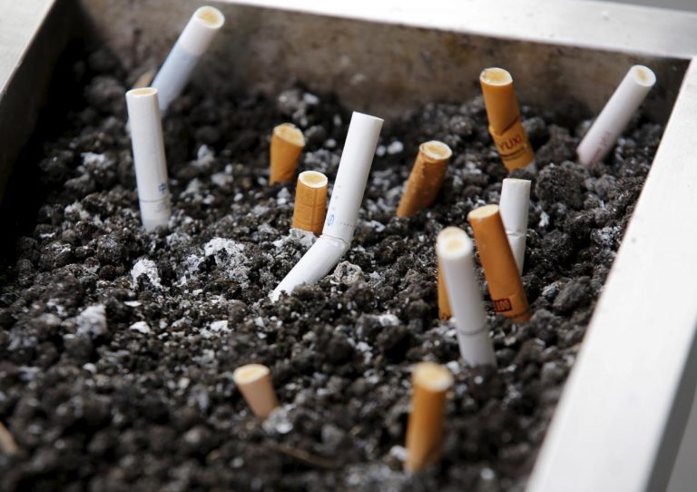 Cigarette butts are seen at an ash tray at a smoking area outside a shopping mall in Beijing, China