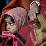 A girl wrapped in a shawl looks on as she waits along with her mother for a train at a railway station on a cold winter morning in New Delhi, India January 3, 2018. Credit: Reuters/Saumya Khandelwal