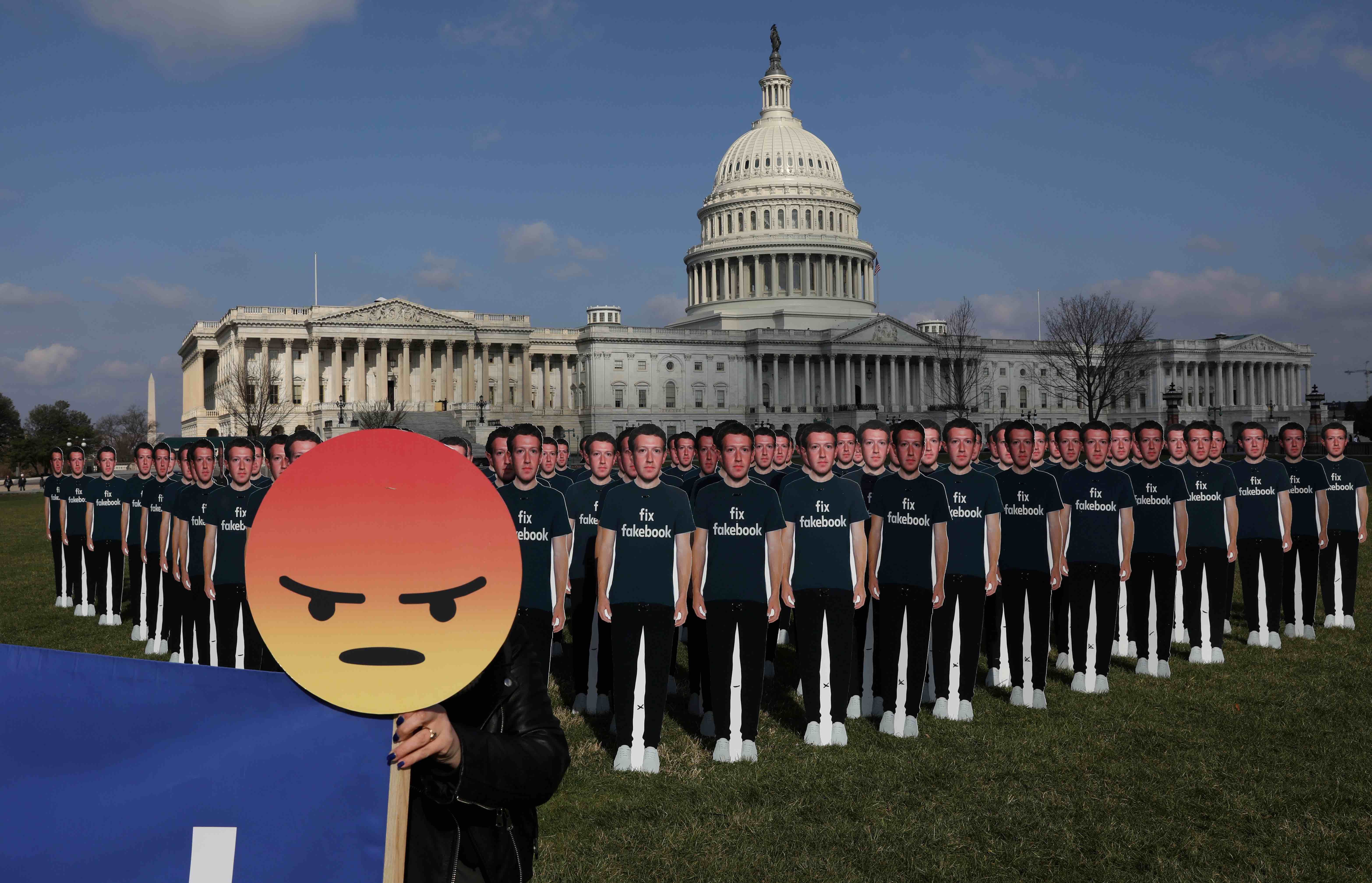 Chelsea Hornick-Becker of Avaaz.org holds a protest sign in front of dozens of cardboard cut-outs of Mark Zuckerberg outside of the Capitol Building in Washington. Credit: Reuters/Leah Millis