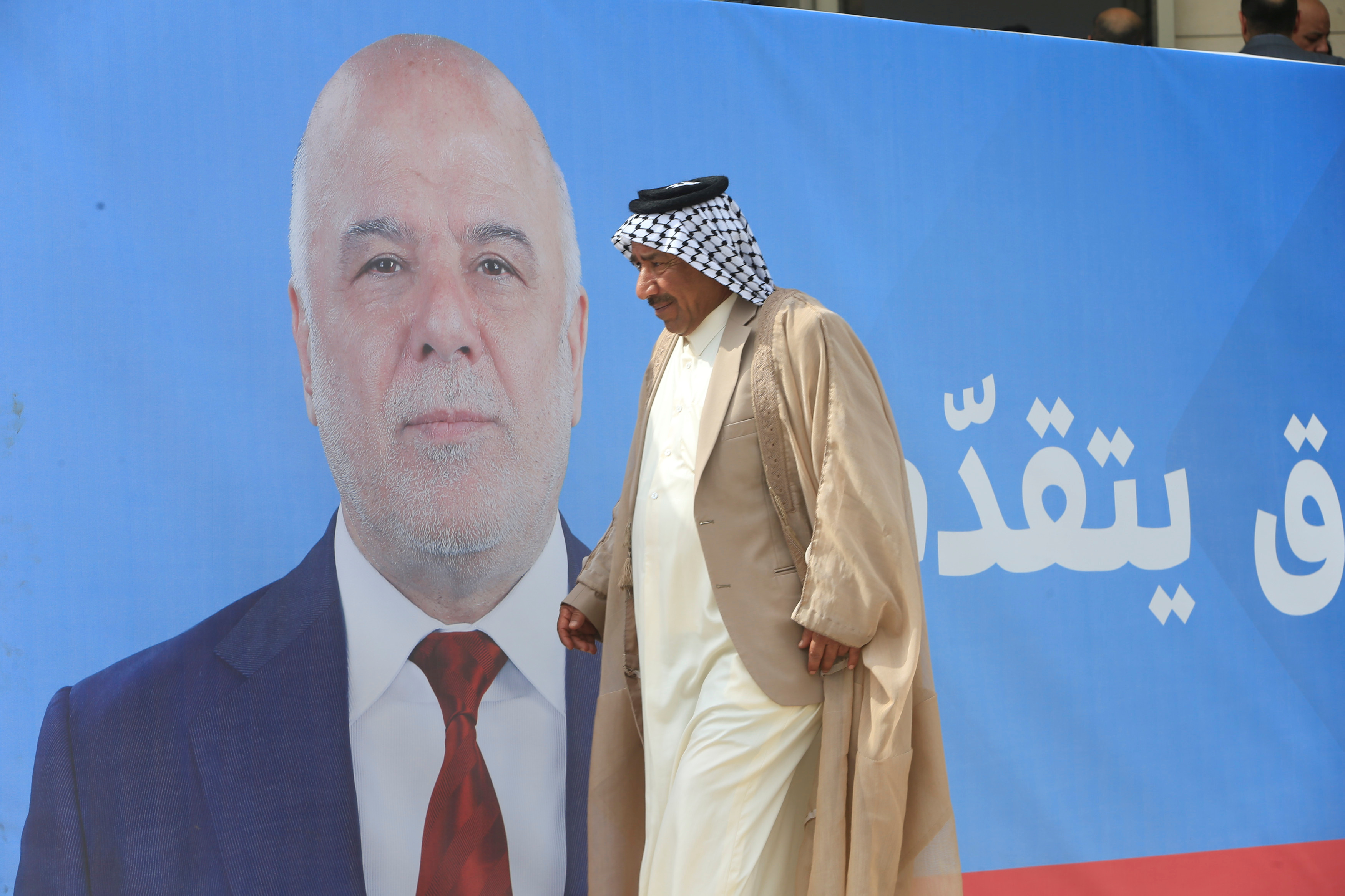 A man walks past a campaign poster of Iraqi Prime Minister Haidar al-Abadi ahead of the parliamentary election, in Najaf, Iraq May 3, 2018. Picture taken May 3, 2018. Credit: Reuters/Alaa al-Marjani