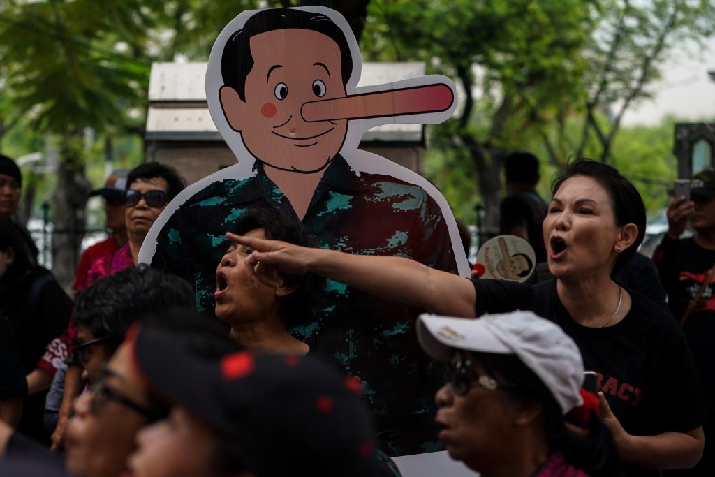 Anti-government protesters gather near a cardboard cut-out mocking Thailand's Prime Minister Prayuth Chan-o-cha as Pinocchio during a protest to demand that the military government hold a general election by November, in Bangkok, Thailand, May 22, 2018. Credit: Reuters/Athit Perawongmetha
