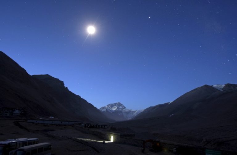 The first light of dawn illuminates Mount Everest as the moon shines above and a toilet block is seen in the foreground in the Tibet Autonomous Region, China, April 29, 2008. Credit: Reuters/David Gray/Files