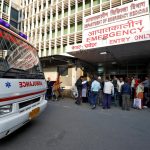 An ambulance arrives as people stand at the entrance of the emergency department of a government-run hospital in New Delhi