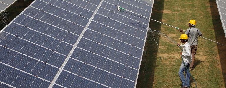 FILE PHOTO: File photo of workers cleaning photovoltaic panels inside a solar power plant in Gujarat