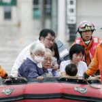 Local residents sit in a boat as they are rescued from a flooded area at a hospital in Kurashiki