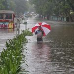 A man wades through a water-logged road during rains in Mumbai