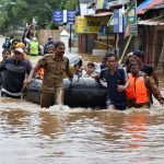 Rescuers evacuate people from a flooded area to a safer place in Aluva