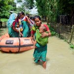 Flood-affected people arrive at a relief camp after they were evacuated from a flooded area at a village in Barpeta district