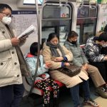 Man wearing a mask reads on the subway in Beijing