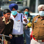 Punjab police personnel wearing protective masks in the wake of the novel coronavirus scare (COVID-19) guide a commuter in Bathinda, Friday, March 13, 2020. Photo: PTI