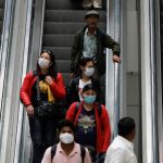 Passengers wearing protective masks travel on an escalator at an airport terminal following an outbreak of the coronavirus disease (COVID-19), in New Delhi
