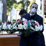 FILE PHOTO: Cemetery workers and funeral agency workers in protective masks transport a coffin of a person who died from coronavirus disease (COVID-19), into a cemetery in Bergamo