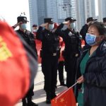 Police officers salute as a medical worker from outside Wuhan arrives at the Wuhan Railway Station before leaving the epicentre of the novel coronavirus disease outbreak