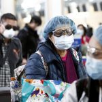 People wearing face masks and goggles wait to check in for an international flight at the Vancouver International Airport