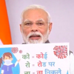 Narendra Modi holds up a banner calling to remain indoors in the light of the coronavirus pandemic. Photo: Twitter