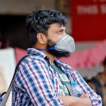 People wearing protective masks wait to board a bus at a terminal amid coronavirus fears, in Kochi