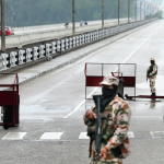A security person stands guard at Jammu & Kashmir National Highway, during day-3 of a nationwide lockdown imposed in the wake of the coronavirus pandemic, in Jammu. Photo: PTI