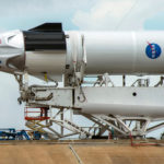 Crews work on the SpaceX Crew Dragon, attached to a Falcon 9 booster rocket, as it sits horizontal on Pad39A