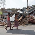 Residents carry tin sheets salvaged from the rubble of a damaged house in the aftermath of Cyclone Amphan, in South 24 Parganas district