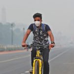 A man wearing a mask rides a cycle on a smoggy morning in New Delhi