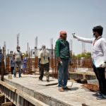 FILE PHOTO: Health worker using an infrared thermometer to measure the temperature of a labourer