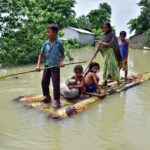 Villagers row a makeshift raft through a flooded field to reach a safer place at the flood-affected Mayong village