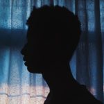 side-view-silhouette-photo-of-man-standing-near-curtain-2245373