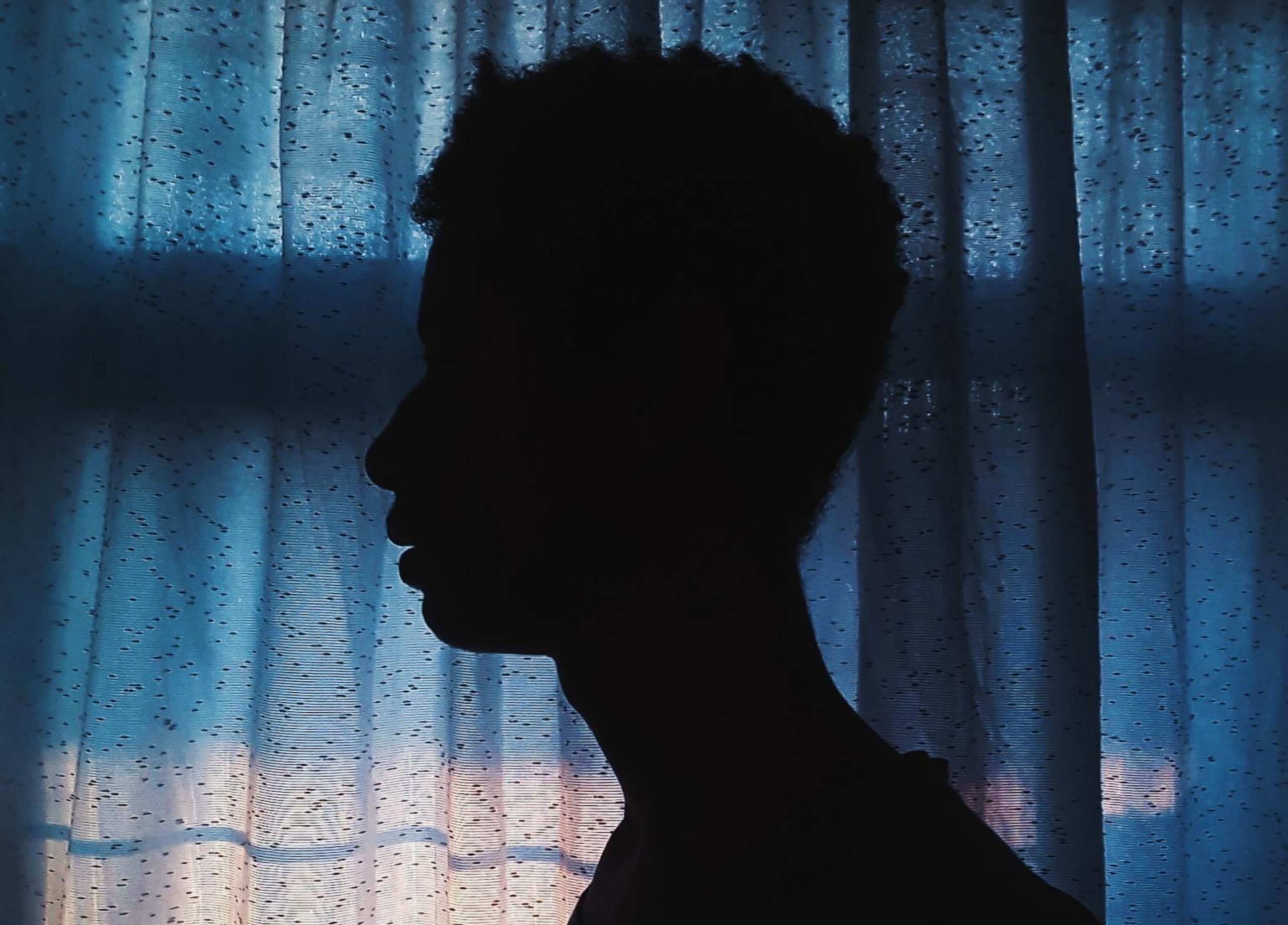 side-view-silhouette-photo-of-man-standing-near-curtain-2245373