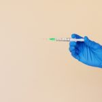 crop-nurse-with-syringe-on-beige-background-4492047