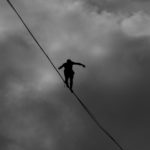 low-angle-photo-grayscale-of-person-tightrope-walking-2225771