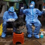 Healthcare workers rest in front of a fan during a check up campaign for the coronavirus disease (COVID-19) at a slum area in Mumbai