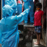 A healthcare worker checks the temperature of a resident during a medical campaign for the coronavirus disease (COVID-19) at a slum area in Mumbai