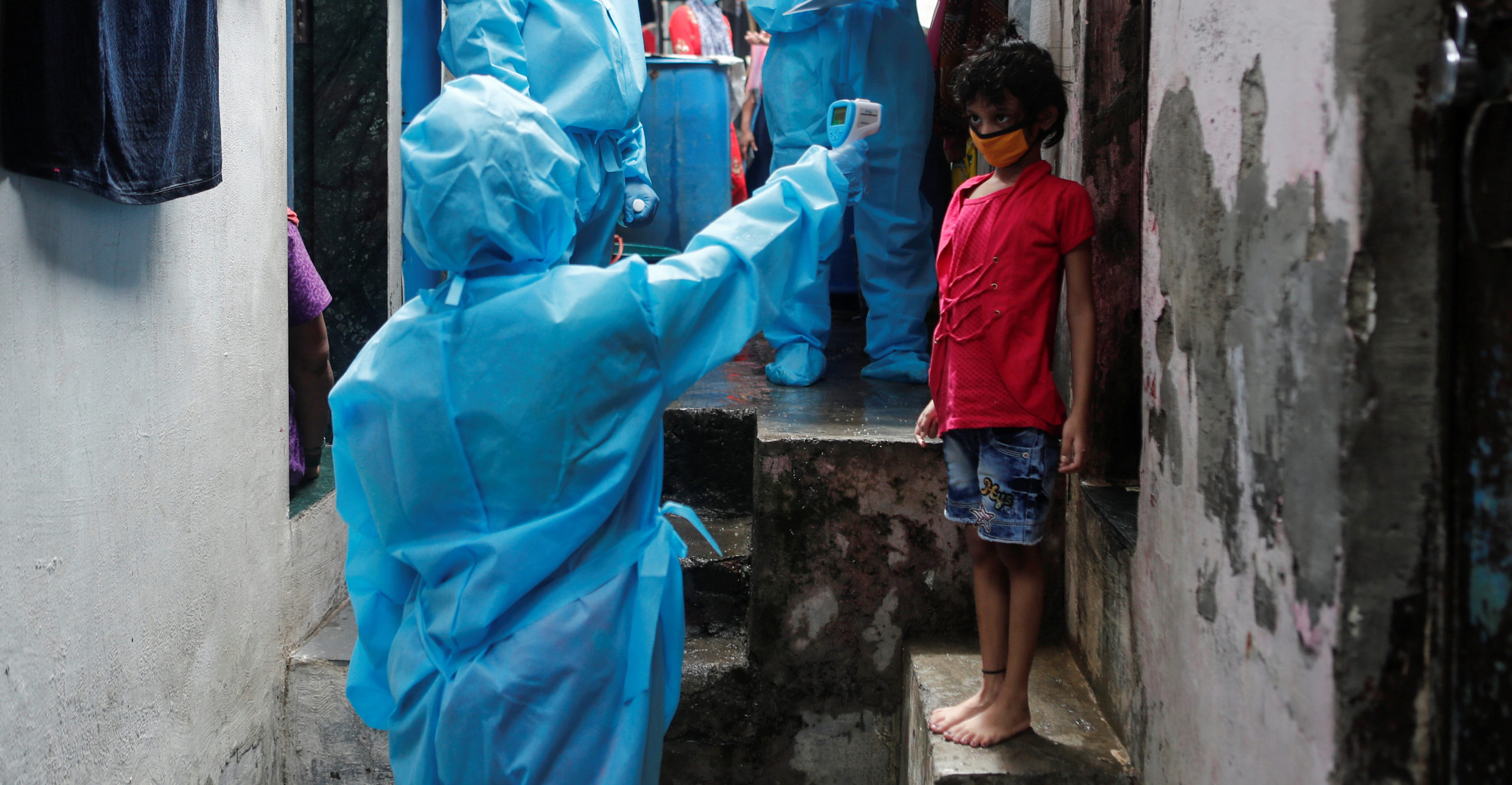 A healthcare worker checks the temperature of a resident during a medical campaign for the coronavirus disease (COVID-19) at a slum area in Mumbai