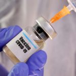 FILE PHOTO: A woman holds a small bottle labeled with a "Vaccine COVID-19" sticker and a medical syringe in this illustration