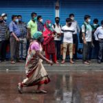Passengers wearing masks wait in a queue at a bus terminus to board a bus, after authorities eased lockdown restrictions that were imposed to slow the spread of the coronavirus disease in Kolkata