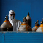 A medical worker stands next to an oxygen cylinder at the Yatharth Hospital in Noida
