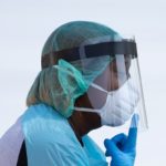 Healthcare worker points towards her mask at COVID-19 drive in testing location in Houston, Texas