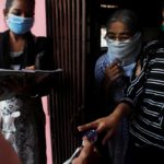Community health volunteers check the pulse of a resident during a check-up campaign for the coronavirus disease (COVID-19) in Mumbai