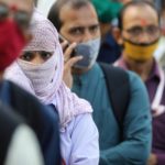 People wearing protective masks wait in line to board a bus amidst the spread of the coronavirus disease (COVID-19) in Mumbai