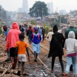 A schoolgirl walks among residents along the Kenya-Uganda railway line during the partial reopening of schools, in Nairobi