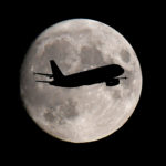 otA passenger plane passes in front of the moon as it makes its final landing approach to Heathrow Airport in London