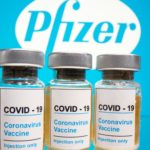 FILE PHOTO: Vials and medical syringe are seen in front of Pfizer logo in this illustration