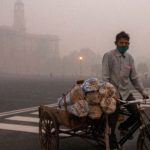 A man transports goods on his cycle cart near the parliament on a smoggy morning in New Delhi