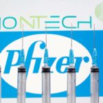 FILE PHOTO: Syringes are seen in front of displayed Biontech and Pfizer logos in this illustration