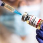FILE PHOTO: A woman holds a medical syringe and a small bottle labeled "Coronavirus COVID-19 Vaccine