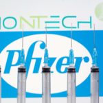 FILE PHOTO: Syringes are seen in front of displayed Biontech and Pfizer logos in this illustration