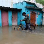 A man pushes his bicycle through a water-logged neighbourhood after Cyclone Nivar's landfall, in Chennai