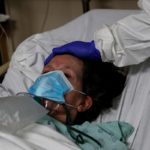 FILE PHOTO: Donna Plummer, a coronavirus disease (COVID-19) positive patient, looks on as Patient Care Technician Fanta Keita comforts her laying on an emergency room bed at Roseland Community Hospital on the South Side of Chicago, Illinois