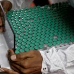 FILE PHOTO: An employee in personal protective equipment (PPE) removes vials of AstraZeneca's COVISHIELD, coronavirus disease (COVID-19) vaccine from a visual inspection machine inside a lab at Serum Institute of India, in Pune